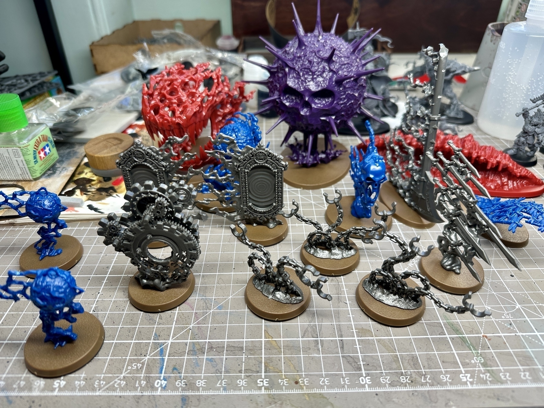 Endless Spell models, by Games Workshop, unpainted, on a messy desk. They are in a variety of coloured plastics